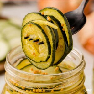 fork with bread and butter pickles on it, jar in background.