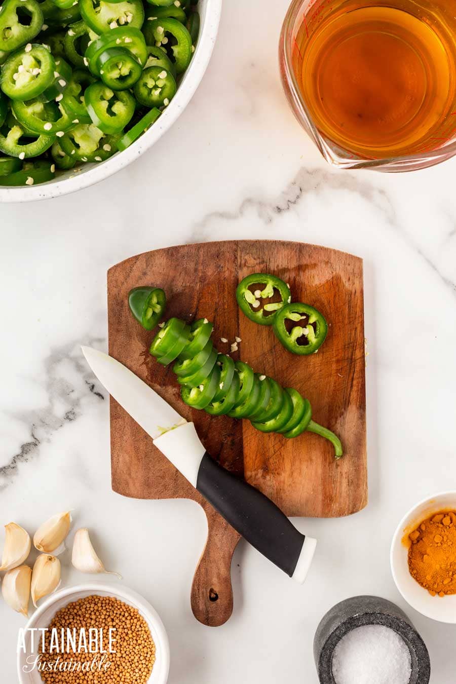 sliced jalapenos on a wooden cutting board.