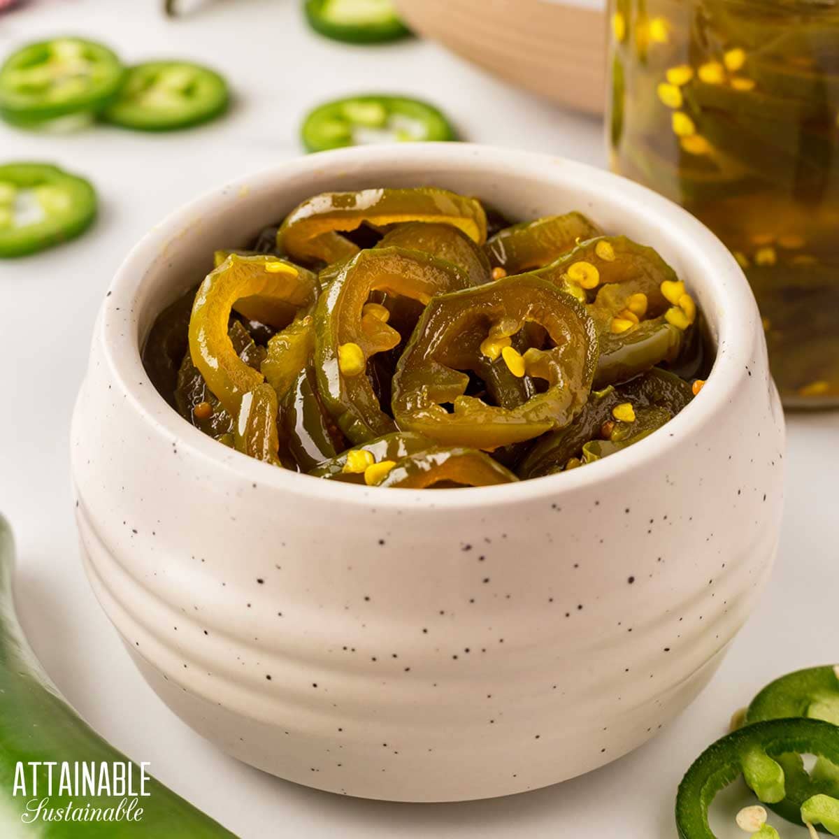 white pottery bowl filled with cowboy candy, candied jalapeno peppers.