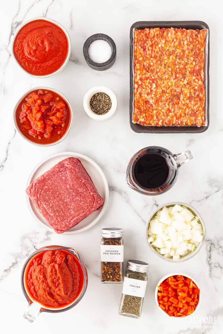 ingredients for meat sauce on a marble background.