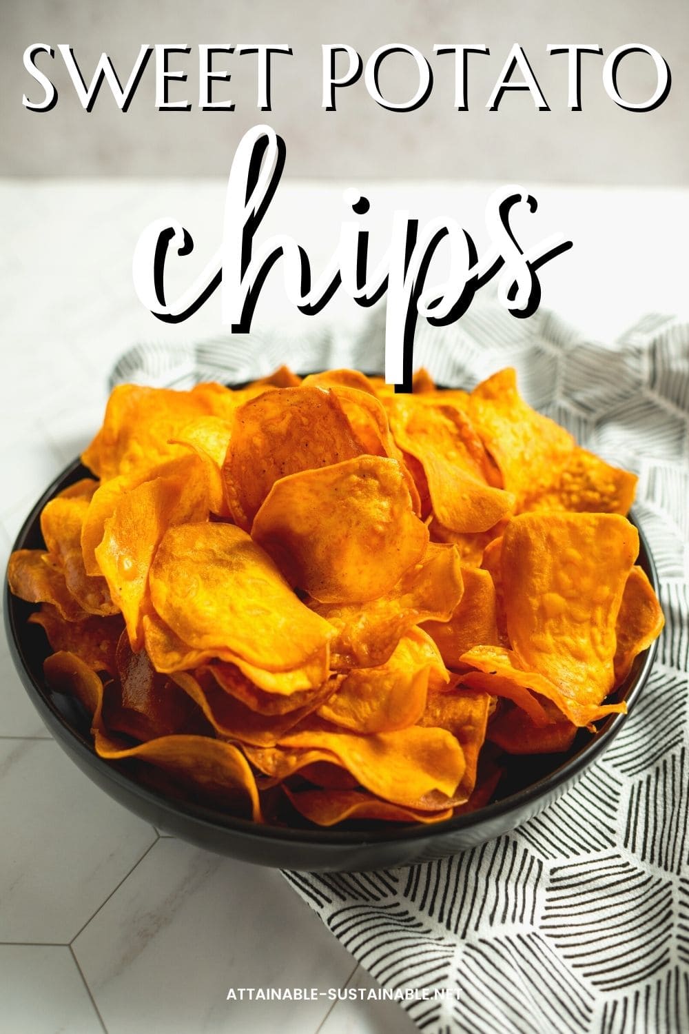 A bowl of homemade sweet potato chips on a black and white patterned napkin, with white lettering on top that reads sweet potato chips.