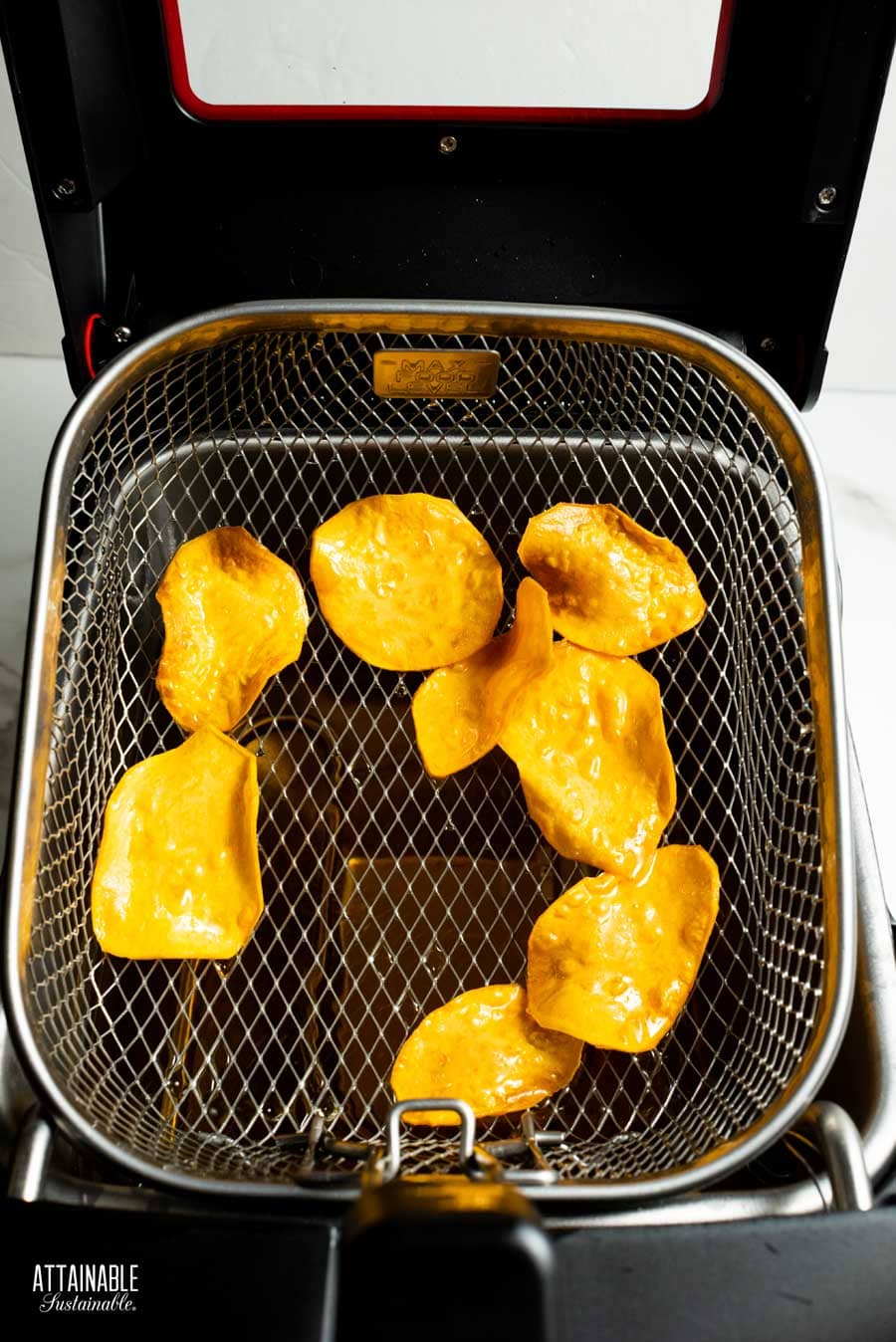 Sweet potato chips cooked and still in the deep fryer basket, pulled out of the oil. 