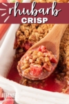 rhubarb crisp in a white baking dish with a serving scooped out in a wooden spoon.