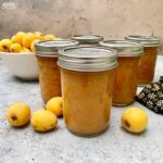 Jars of loquat jam with fresh loquat fruit.