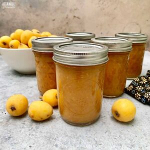 Jars of loquat jam with fresh loquat fruit.