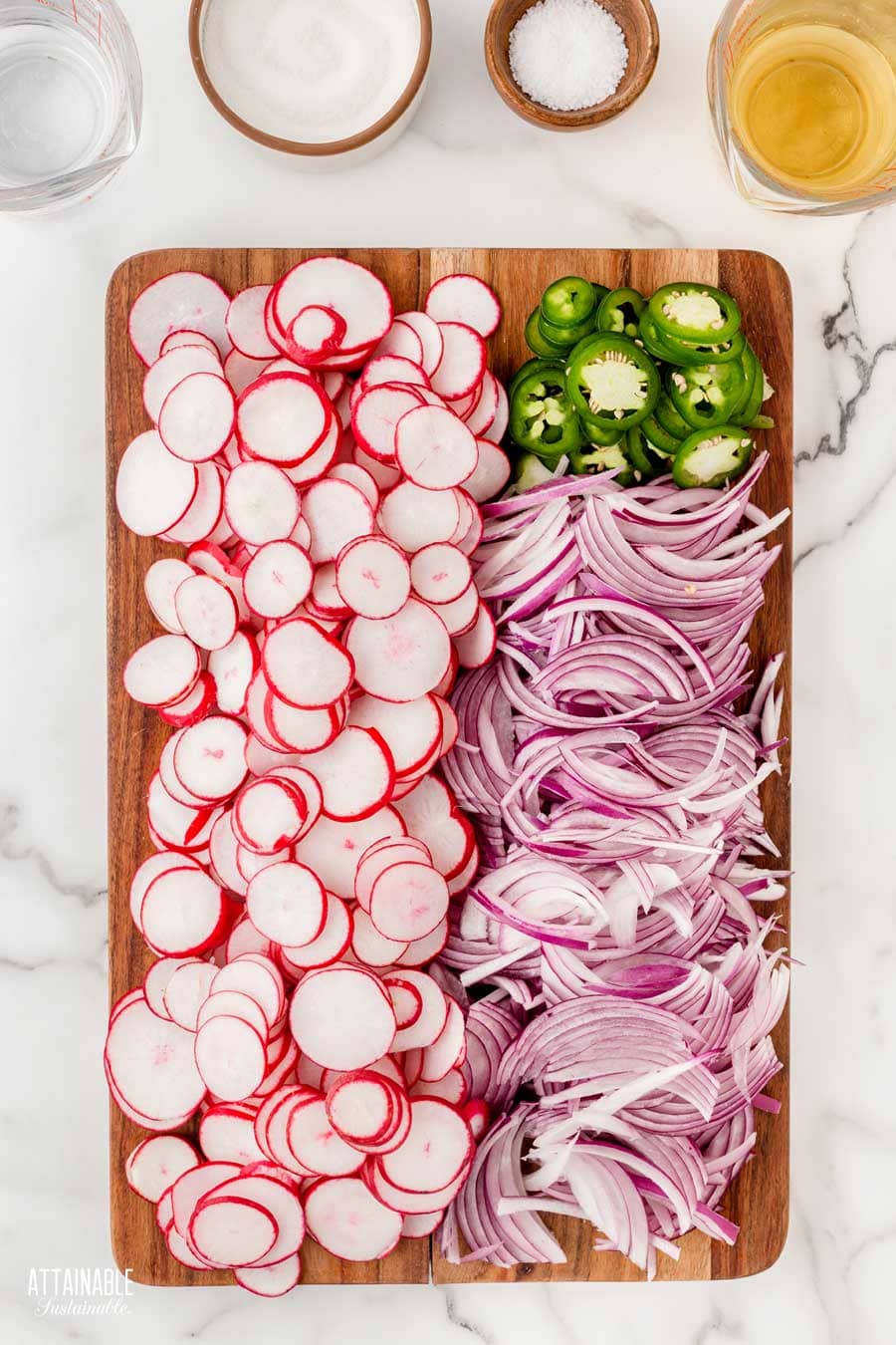sliced radishes, red onions, and jalapeno pepper on a wooden cutting board.