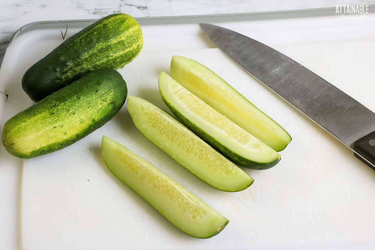 cucumbers on a cutting board, one cut into spears.