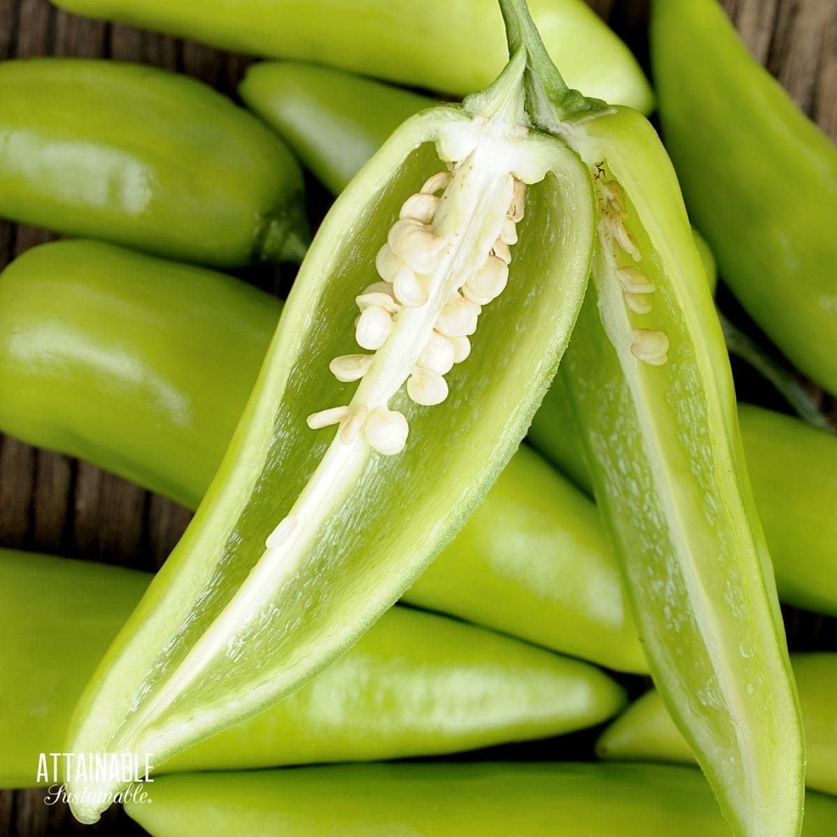 one banana pepper cut in half lengthwise, sitting on more whole peppers.