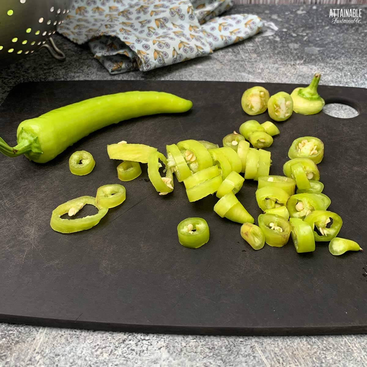 black cutting board with slices of banana peppers.