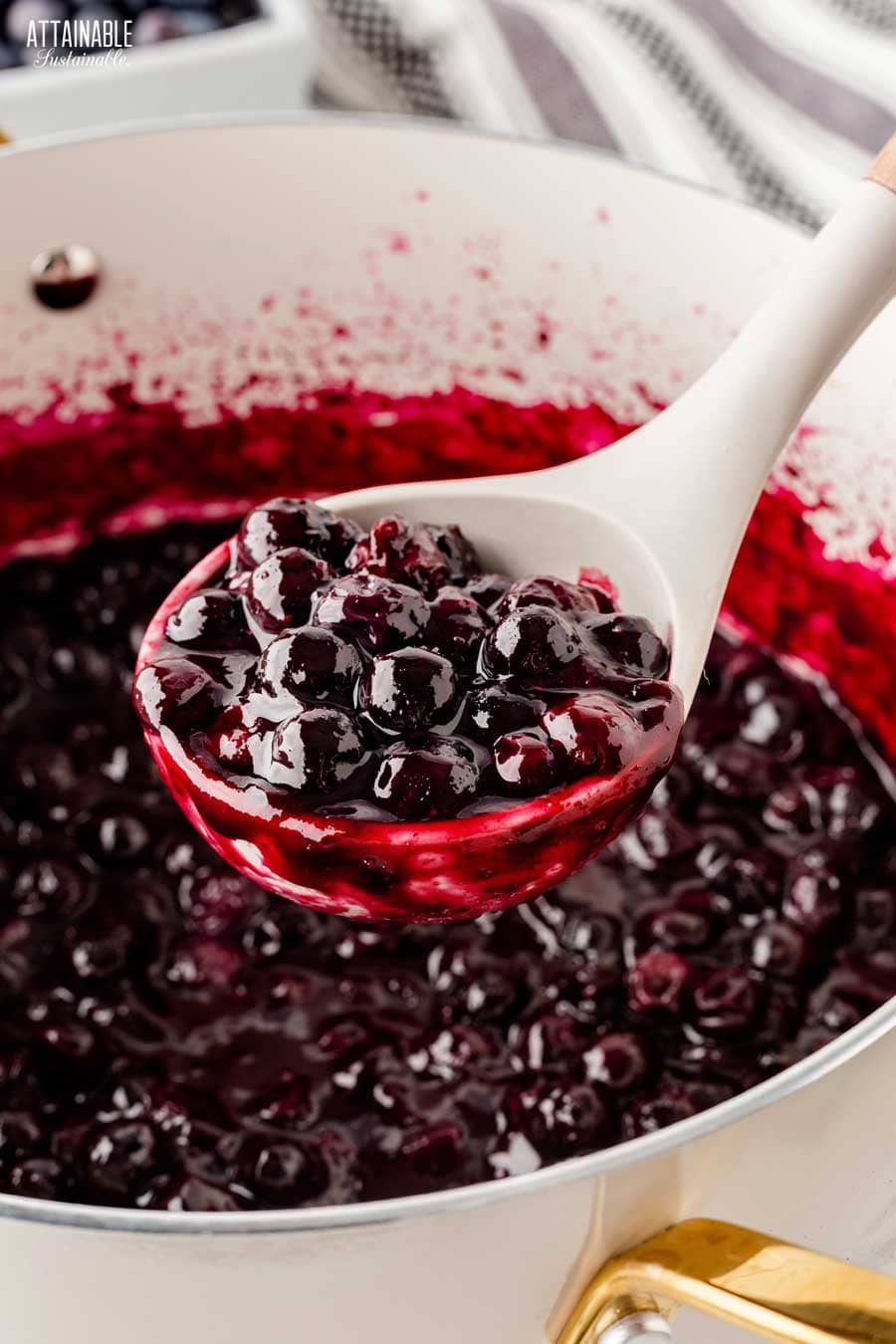 white ladle full of cooked blueberry pie filling. 