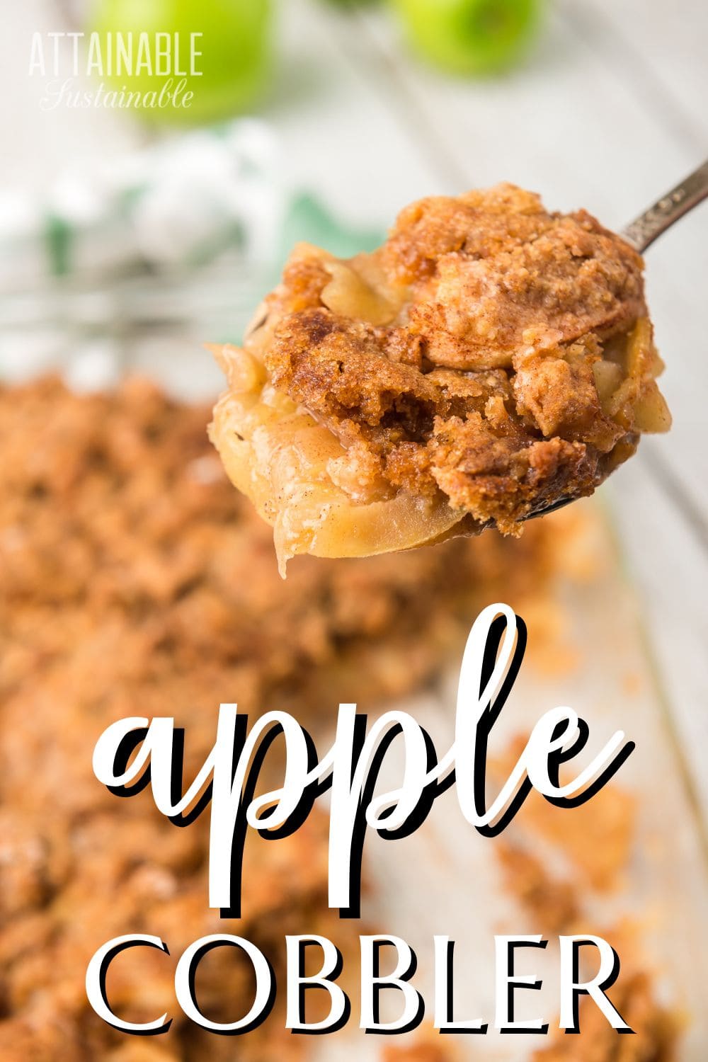 spoonful of apple crisp up close, with a pan of crisp behind.