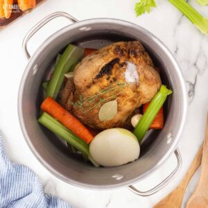 Roasted chicken, onion, celery and carrots in a pot, ready to make chicken broth.