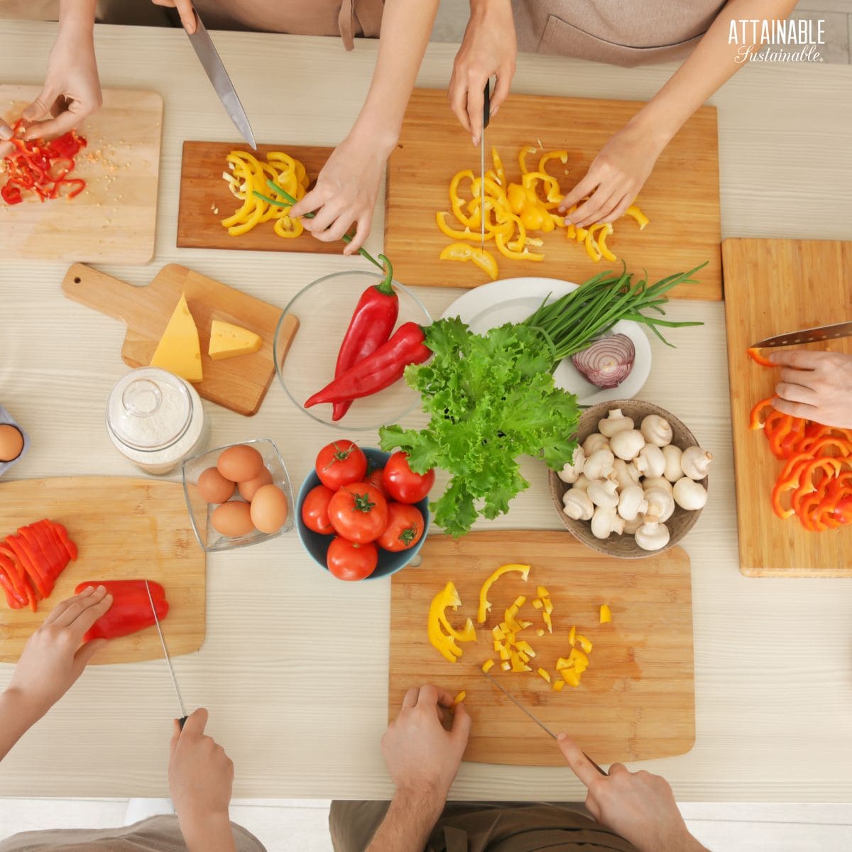 table from above, with cutting boards and 5 people's hands chopping veggies.