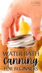 hand placing a ring on a canning jar full of orange fruit spread in preparation for water bath canning.