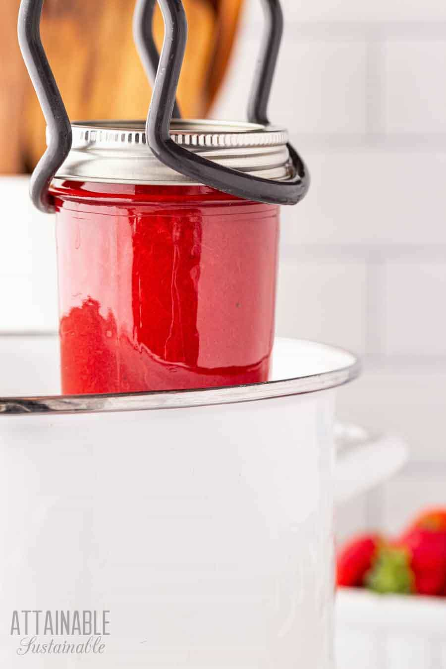 using canning tongs to place jar in canner.