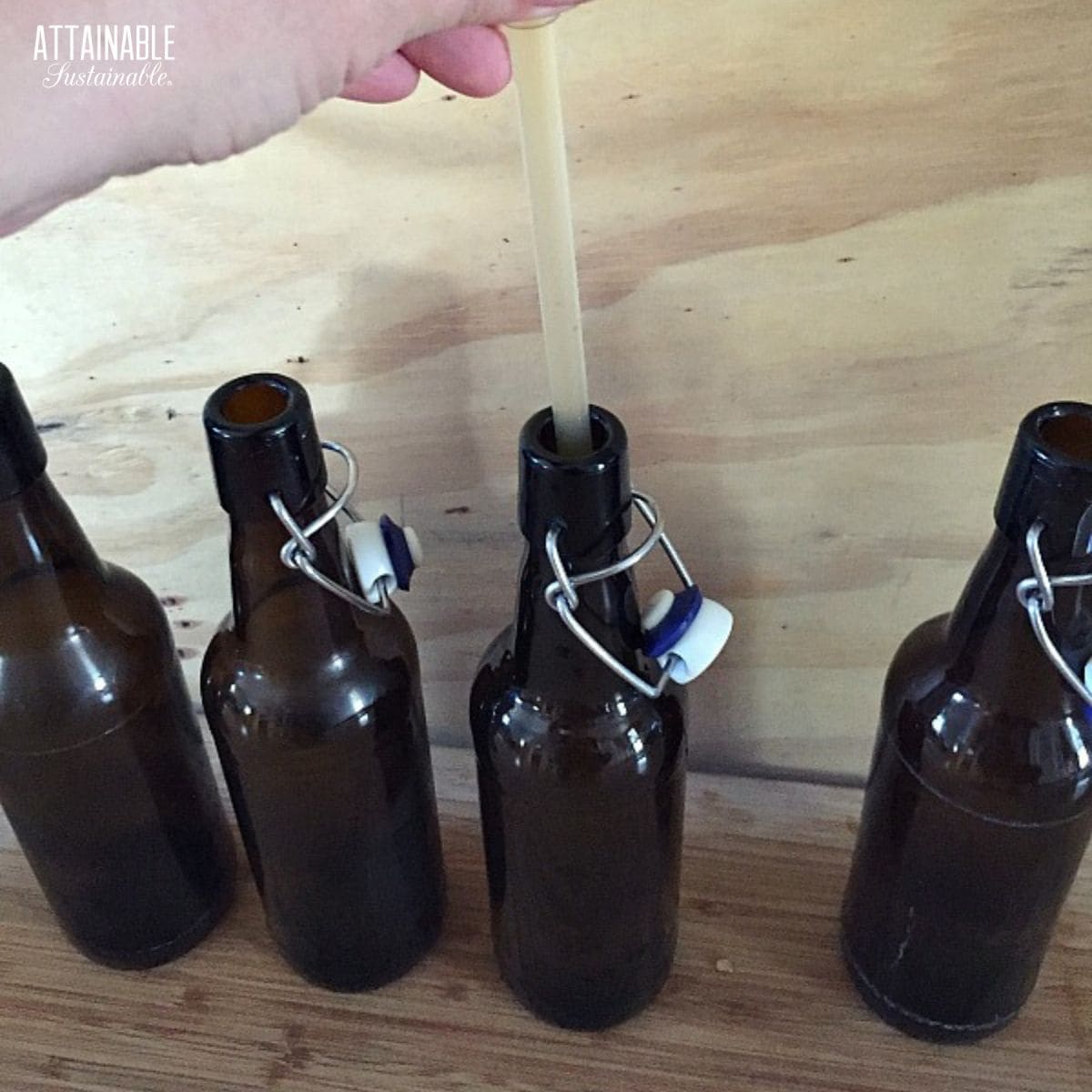 four dark colored swing top bottles prepped for bottling mead.