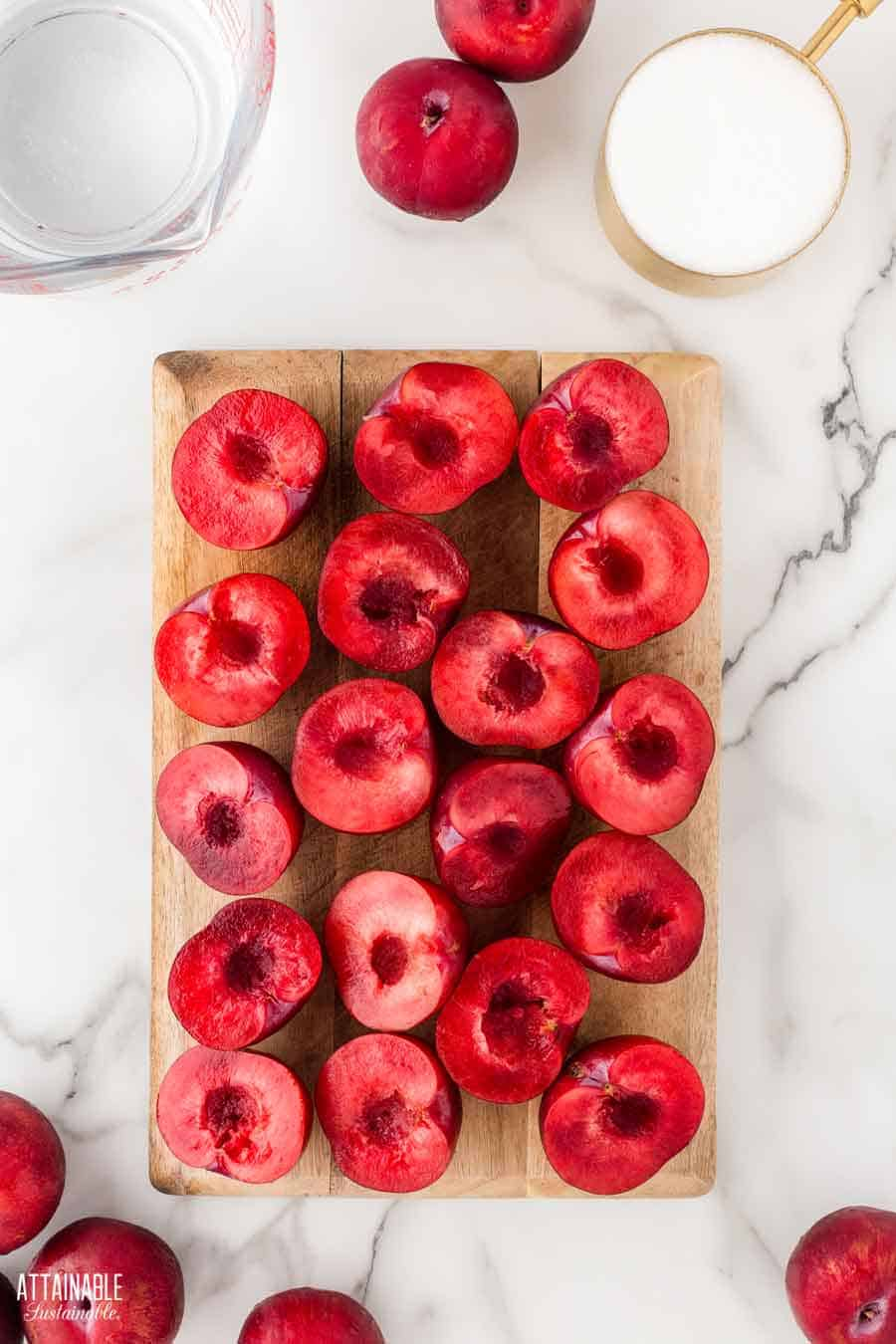 many plum halves, cut side up, on a cutting board. 