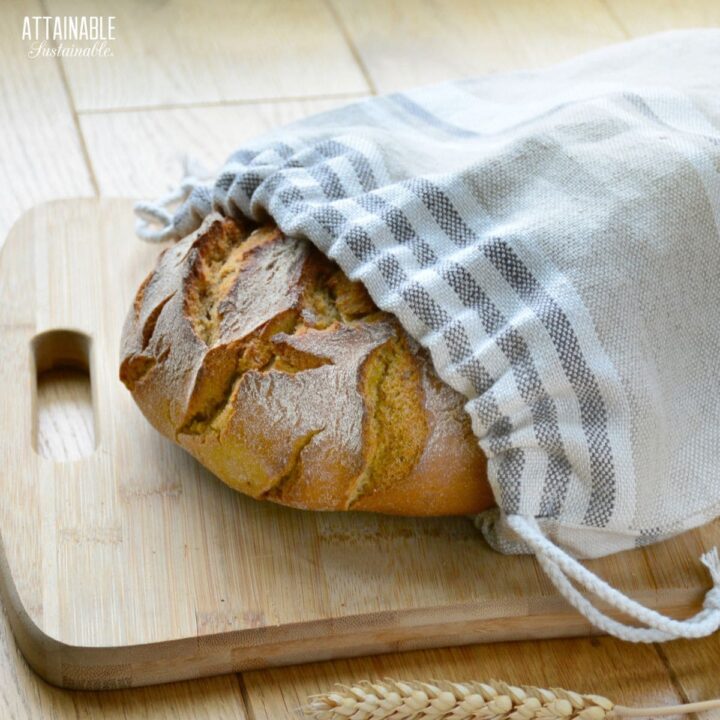 loaf of bread peeking out of a linen bread bag with drawstrings.