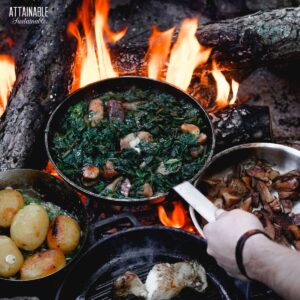 cooking food over an open fire in a frying pan.