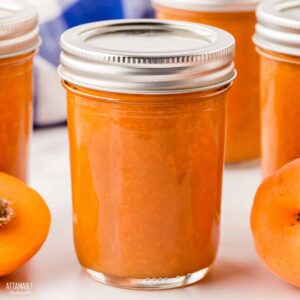 jars of apricot jam, focus on one in center.