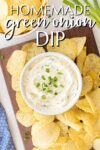 bowl of green onion dip amid potato chips on a wooden tray, from above.