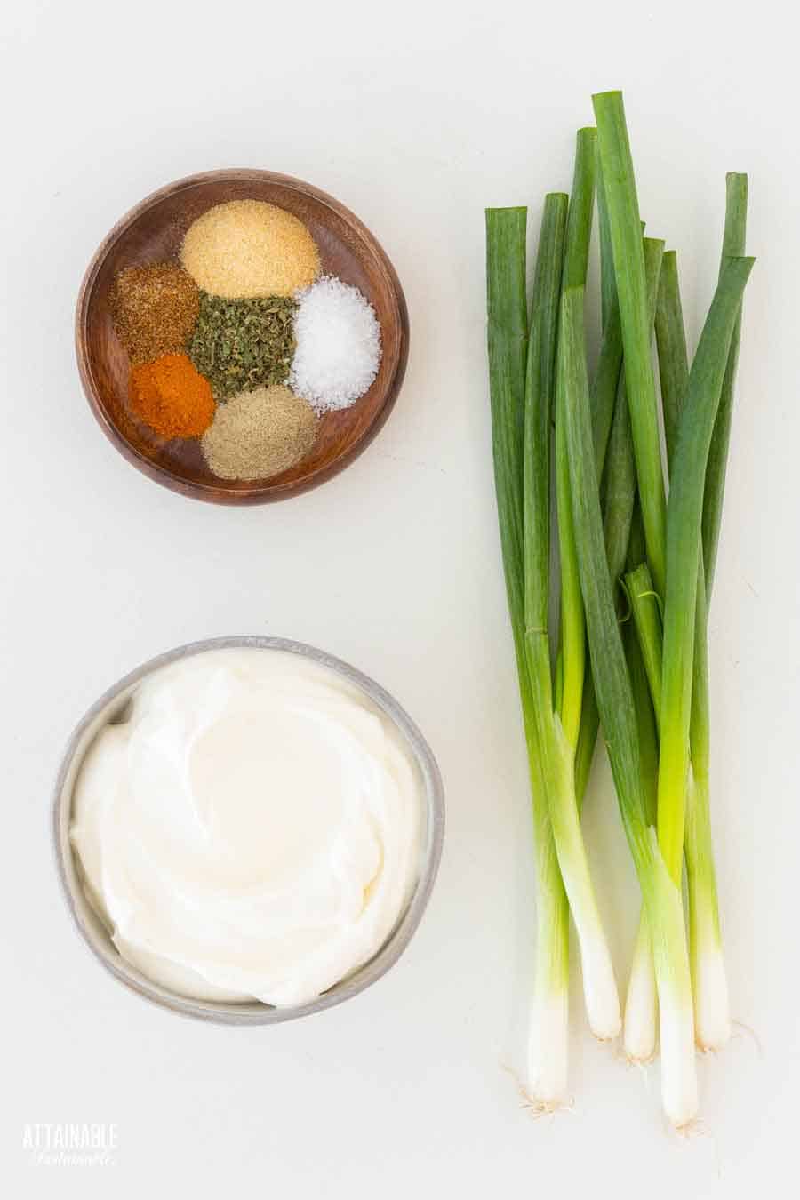 ingredients for making green onion dip: seasonings, sour cream, and fresh green onions.