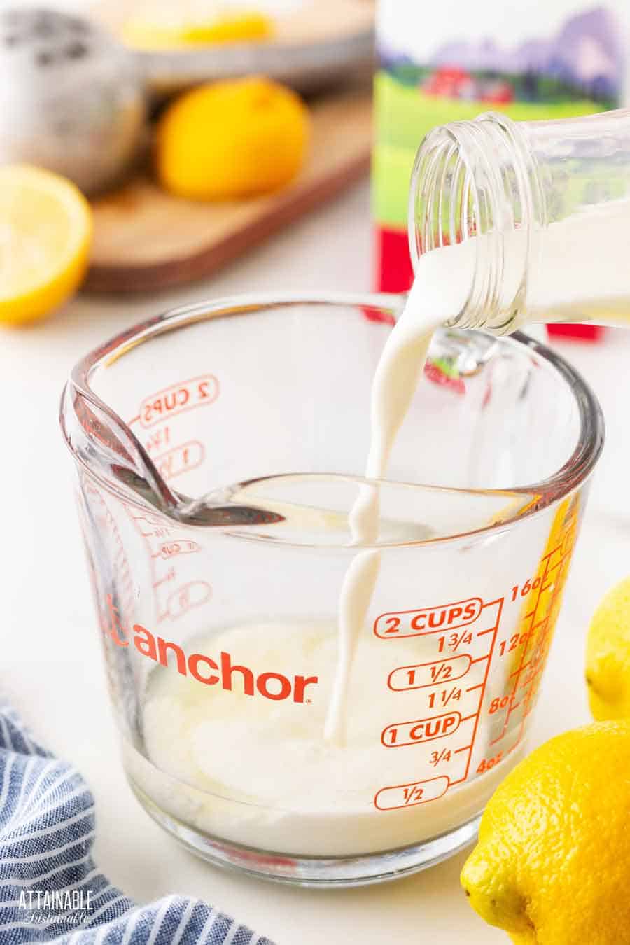 Pouring milk into lemon juice in a measuring cup.