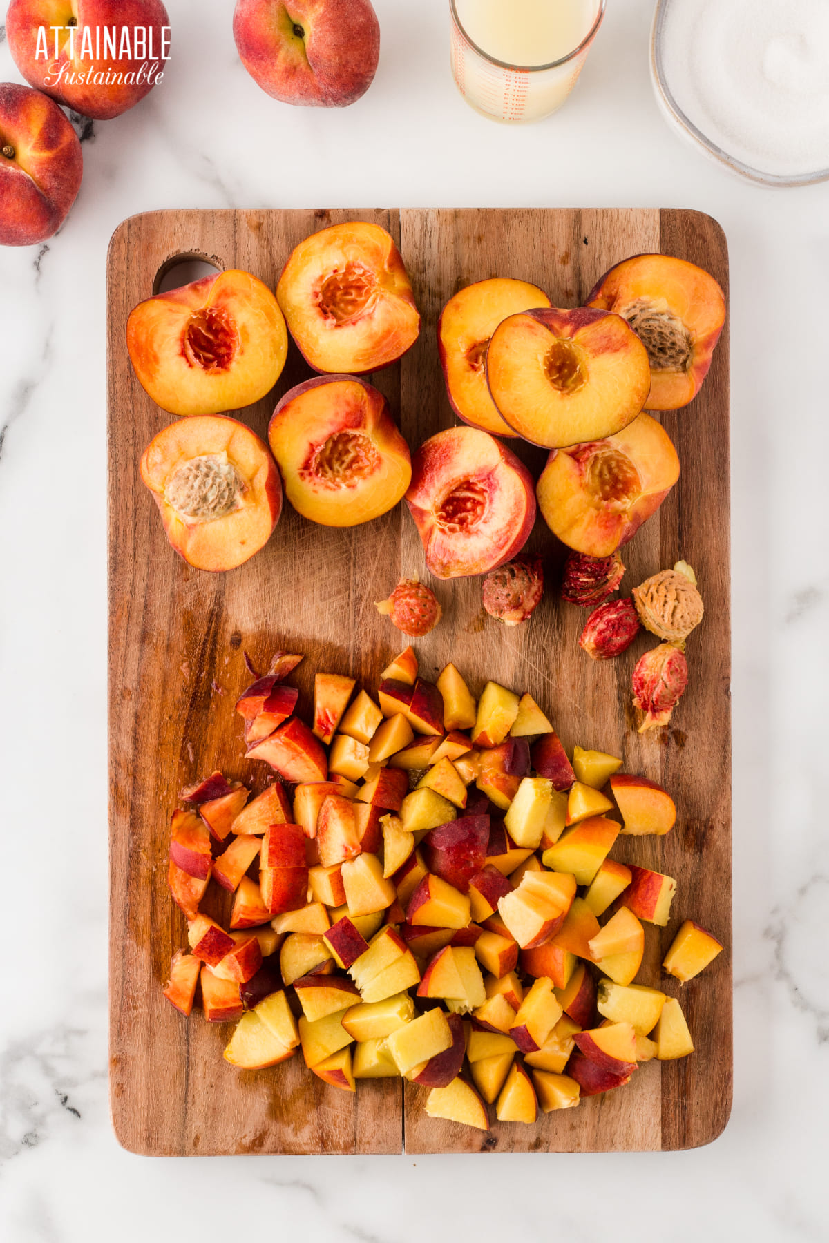 Halved peaches on a wooden cutting board, some diced.
