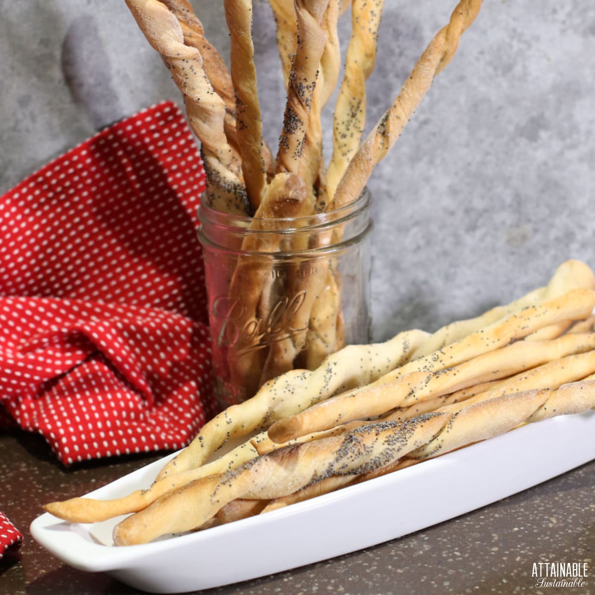 crispy breadstickes in a white tray and standing upright in a glass jar.